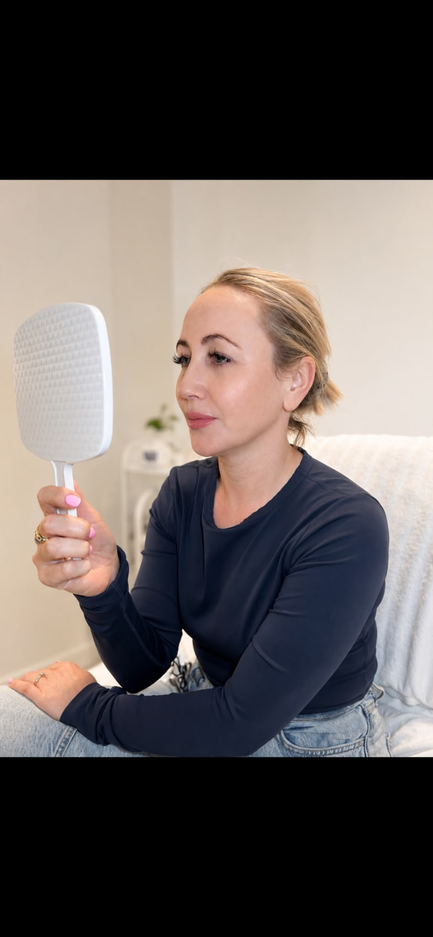 Client reviewing her skin in a hand mirror after treatment at Derma Corner Parramatta